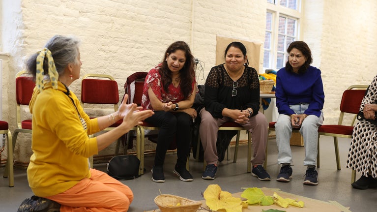 Jasmin Bhanji and community group members looking at leafs, seeds and other materials foraged from Osterley Park.